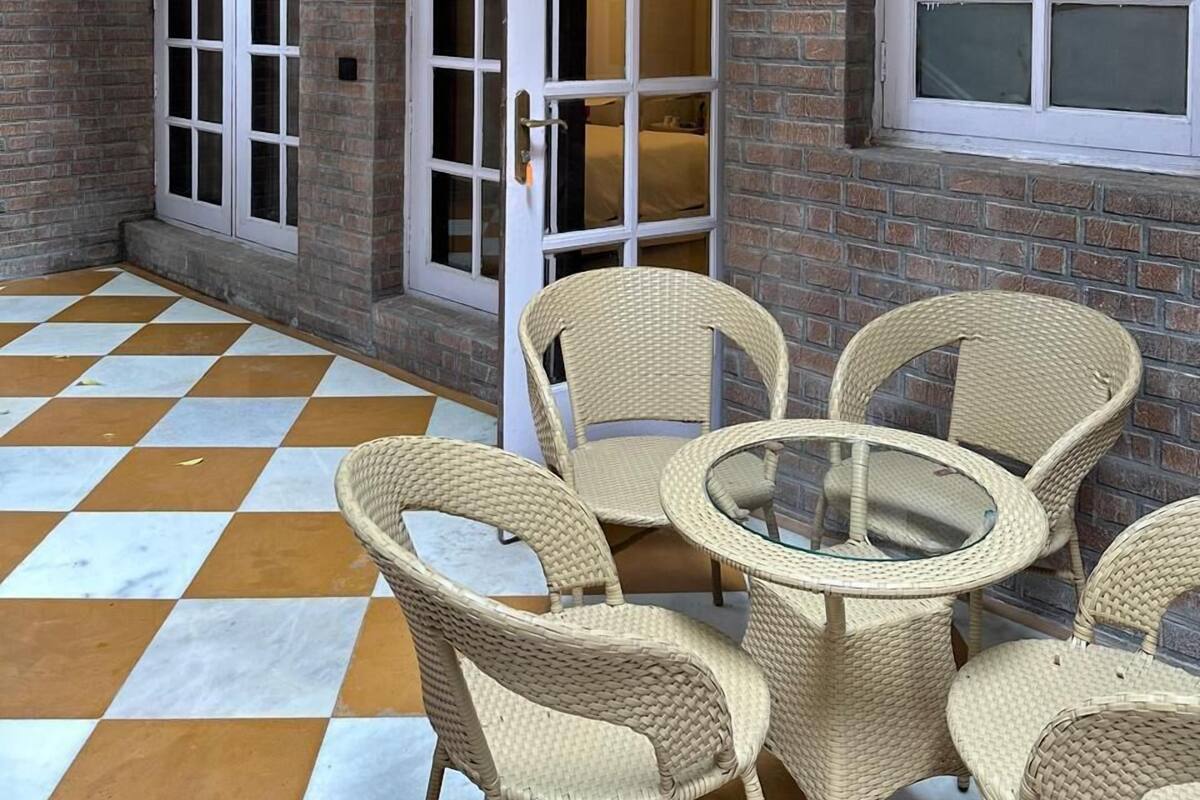 Un espacio al aire libre cubierto con mobiliario de mimbre y piso a cuadros.