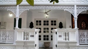 A white building with intricate architectural details, including a balcony with ornate railings and a large central window. - VILLA 33 Bed & Breakfast (New Delhi)