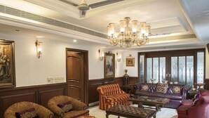 A spacious living room with a chandelier, leather sofas, and a glass coffee table. - VILLA 33 Bed & Breakfast (New Delhi)