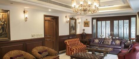 Ein geräumiges Wohnzimmer mit einer Chandelüster, Ledersofas und einem Glastisch.