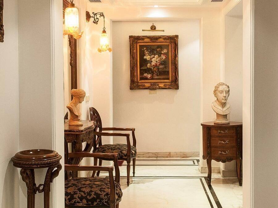 A hallway with a marble floor, a dining area with wooden furniture, and a framed painting on the wall.