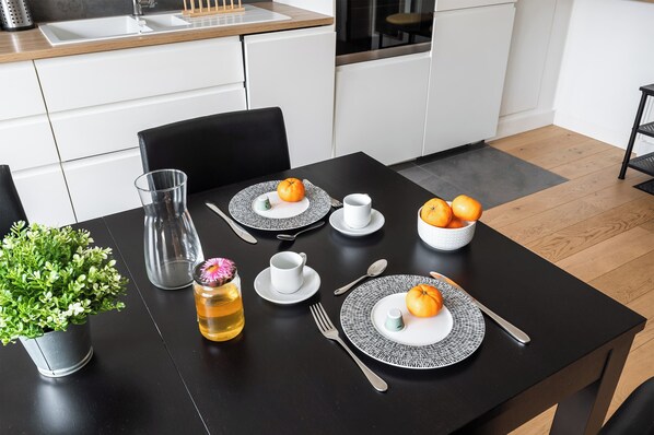 Enjoy meals in this kitchen with a dining table set for a meal, featuring a potted plant and a pitcher with a flower.