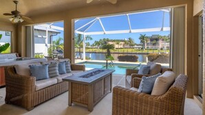 A sunlit outdoor seating area with wicker furniture, a pool, and a view of a residential area. - Punta Gorda Isles 3 Bedroom Pool+Hot Tub Home (Punta Gorda)