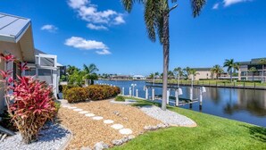 A modern building with a pool, surrounded by palm trees and a well-maintained garden with stepping stones. - Punta Gorda Isles 3 Bedroom Pool+Hot Tub Home (Punta Gorda)