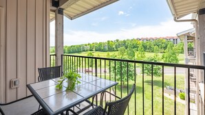 Ein Balkon mit Tisch und Stühlen mit Blick auf eine grüne Landschaft und Gebäude.