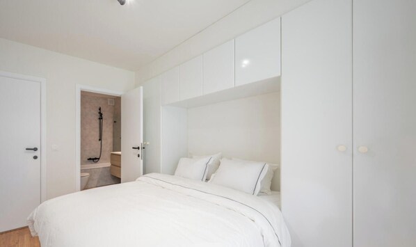 A bedroom with a bed, a wardrobe, and a bathroom visible through an open door. - Urban Floor, A beach breeze around the corner (Knokke-Heist)
