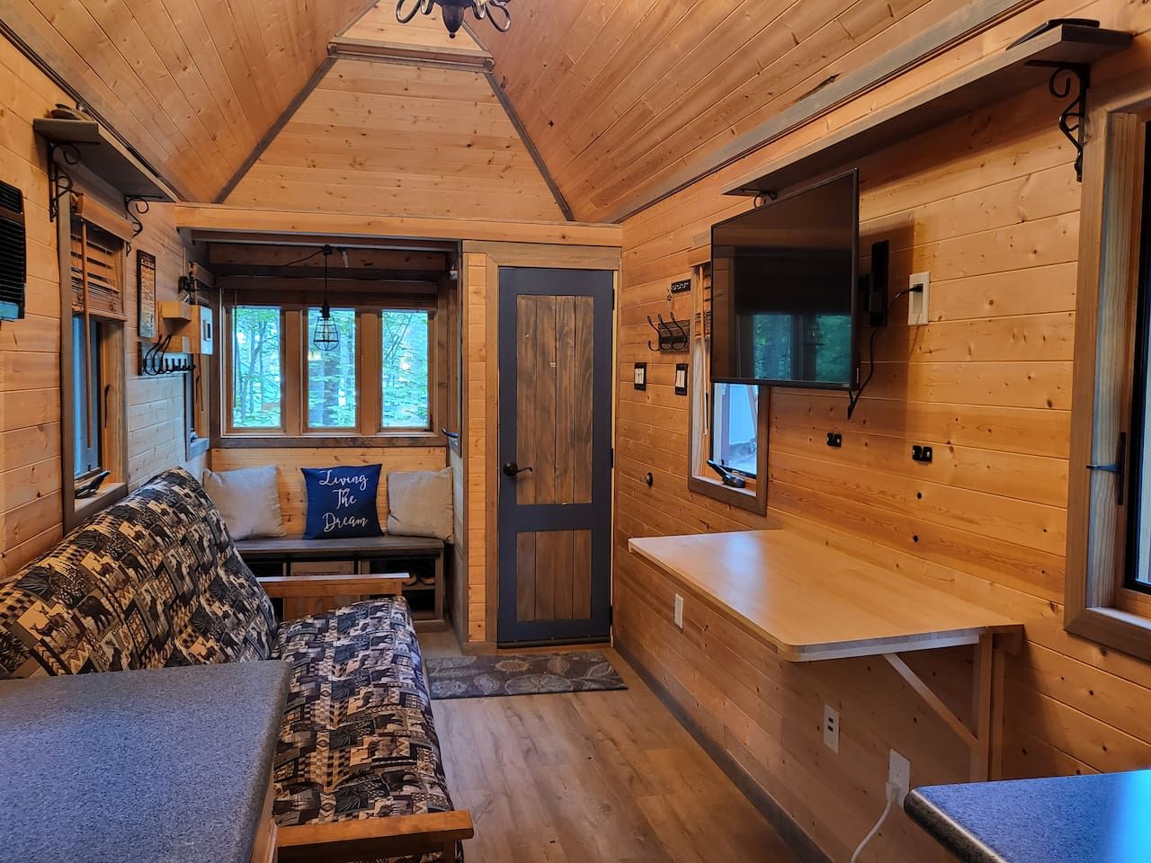 Ein gemütliches Blockhaushaus-Interieur mit einer Couch, einem kleinen Tisch und einem an der Wand montierten Fernseher.