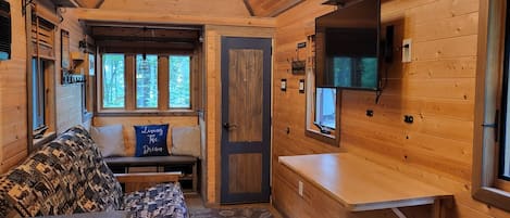 Ein gemütliches Blockhaushaus-Interieur mit einer Couch, einem kleinen Tisch und einem an der Wand montierten Fernseher.