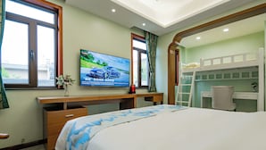 Une chambre d’hôtel avec un lit, un bureau, une télévision et un lit superposé.