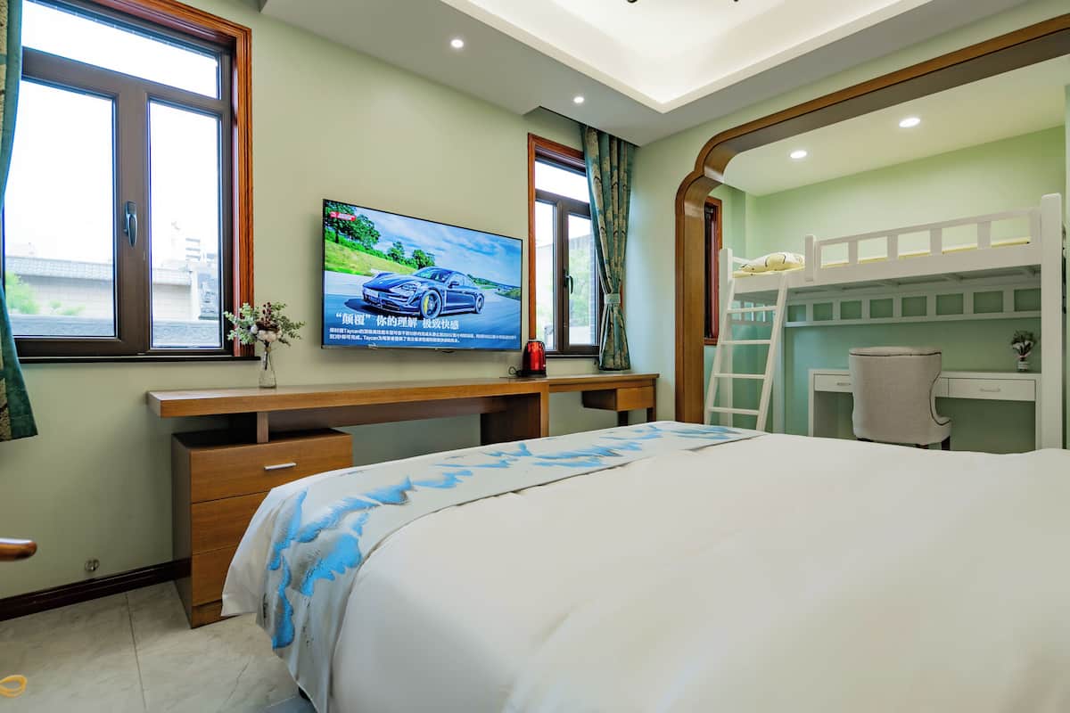 Ein Hotelzimmer mit einem Bett, einem Schreibtisch, einem Fernseher und einem Schlafstockbett.