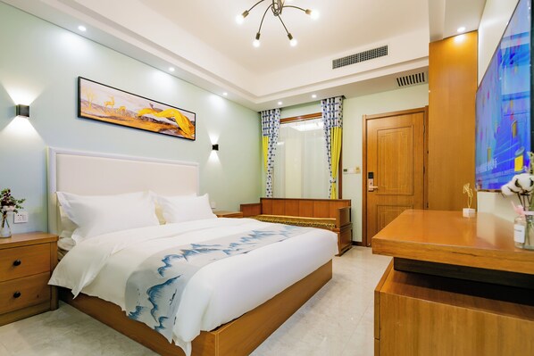Habitación de hotel con una cama grande, cabecera de madera, mesitas de noche, un escritorio y un televisor.