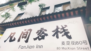 Une enseigne d’hôtel avec des caractères chinois et du texte en anglais indiquant le nom « FanJian Inn » et son adresse, le « 80, rue MaiXian ».