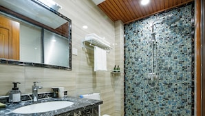 Une salle de bain avec un lavabo en marbre, des toilettes et une douche aux carreaux de mosaïque.