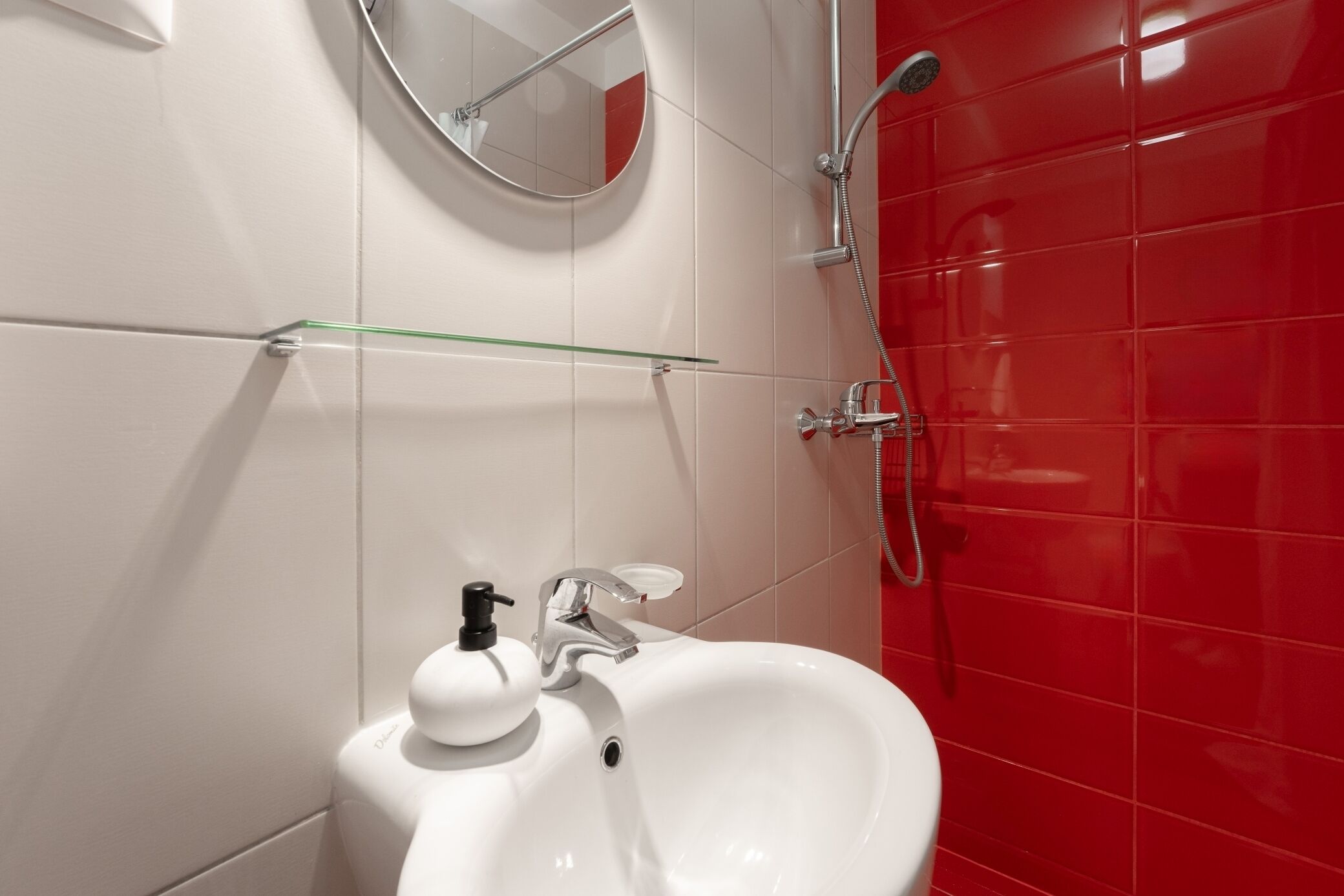 A bathroom with a white sink, a mirror, and a shower.