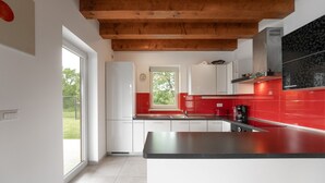 Una cocina moderna con armarios blancos, un salpicadero rojo y una encimera negra.