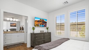 Ein Schlafzimmer mit einem großen Bett, einem Schminktischchen, einem Frisiertisch und einem Landschaftsbild.
