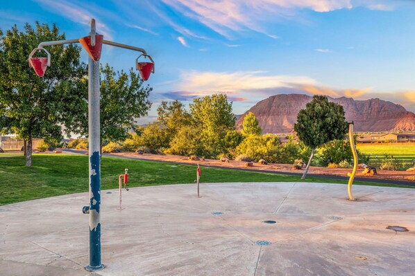 A concrete plaza with a metal sculpture, trees, and a mountain in the background.