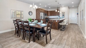 Una cucina moderna con mobili in legno, un frigorifero in acciaio inossidabile e un'area pranzo con tavolo e sedie in legno.