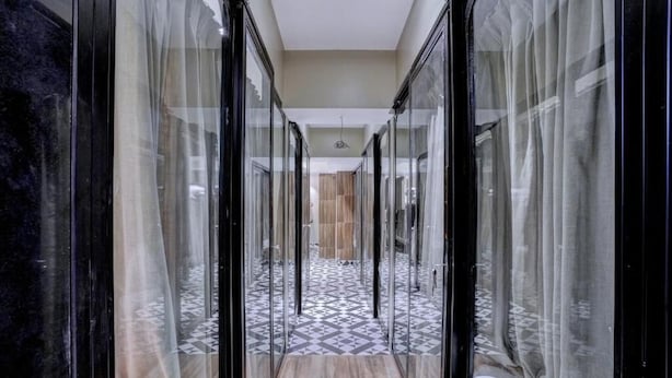 A corridor with glass doors leading to a room with a patterned floor. - Tokyo Stay Hostel (Mumbai)