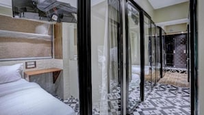 A modern hotel room with a large bed, a wooden shelf, and a glass partition. - Tokyo Stay Hostel (Mumbai)