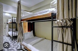 A dormitory-style room with bunk beds, a checkered floor, and curtains. - Tokyo Stay Hostel (Mumbai)