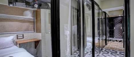 Habitación de hotel con cama, mesita de noche, un ventanal y vistas al exterior.