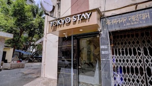 A hotel named "TOKYO STAY" with a glass entrance and a metal gate. - Tokyo Stay Hostel (Mumbai)