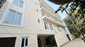 A multi-story residential building with a flat facade, large windows, and balconies. - Hotel Amahi Inn Sector 30 (Gurugram)