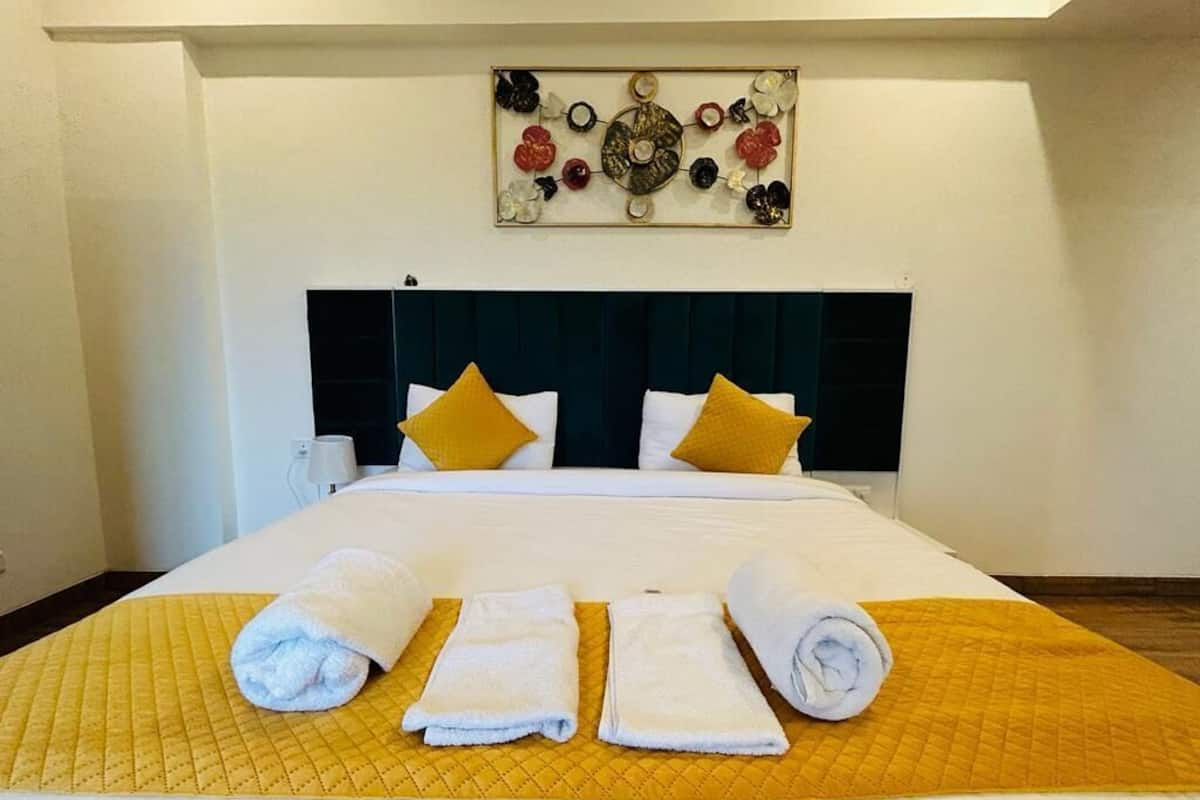 A hotel room with a bed, a headboard, a wall art piece, and towels on the bed.