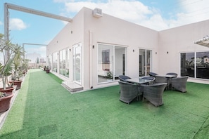 A modern building with a patio area featuring artificial grass, outdoor seating, and potted plants. - Hotel Amahi Inn Sector 30 (Gurugram)