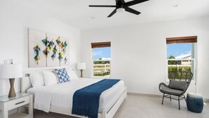Ein modernes Schlafzimmer mit Bett, Nachttischen, Deckenventilator und Blick ins Freie.