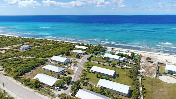 Luftaufnahme eines Küstenresorts mit mehreren Gebäuden, einem Strand und dem Meer.