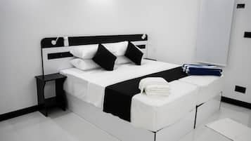 A modern hotel room with a black and white bed, a nightstand, and a neatly made bed with a folded towel.