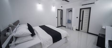 Ein modernes Hotelzimmer mit Bett, Nachttisch, Deckenventilator, Klimaanlage und Kleiderschrank.