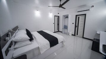 Una habitación de hotel moderna con cama, mesita de noche, ventilador de techo, aire acondicionado y armario.