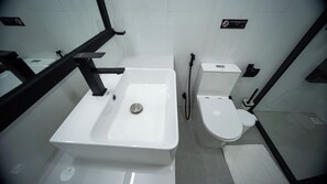 Un baño moderno con lavamanos, inodoro y bidé blancos.