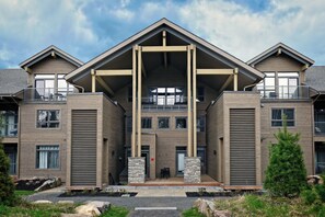 A modern multi-story building with a central atrium, balconies, and a stone facade.