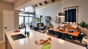 Une cuisine moderne dotée d’un grand îlot central, d’un coin repas et offrant une vue sur l’extérieur.