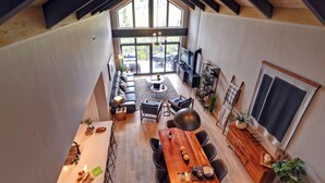 Un loft spacieux avec de hauts plafonds, un coin repas avec une longue table en bois et un coin salon confortable avec un canapé et des fauteuils.