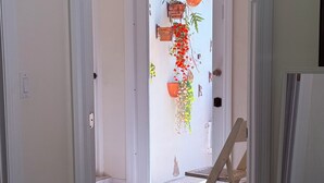 A hallway with a tiled floor, a wooden chair, and a door with hanging plants. - Glamping Miami Farm area RV friendly between Kendall and Key Largo hookup ready! (Miami)