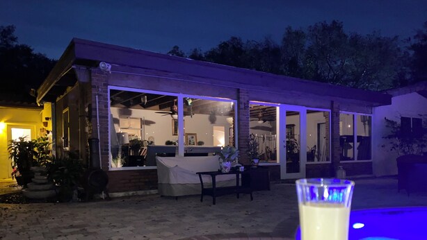 A covered outdoor area with a pool, a glass table, and a patio with a chair. - Glamping Miami Farm area RV friendly between Kendall and Key Largo hookup ready! (Miami)