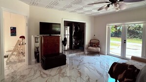 A spacious room with a marble floor, a ceiling fan, a television, and a view through the glass door. - Glamping Miami Farm area RV friendly between Kendall and Key Largo hookup ready! (Miami)