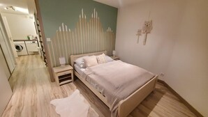 A bedroom with a bed, nightstands, a wall-mounted lamp, and a small rug.