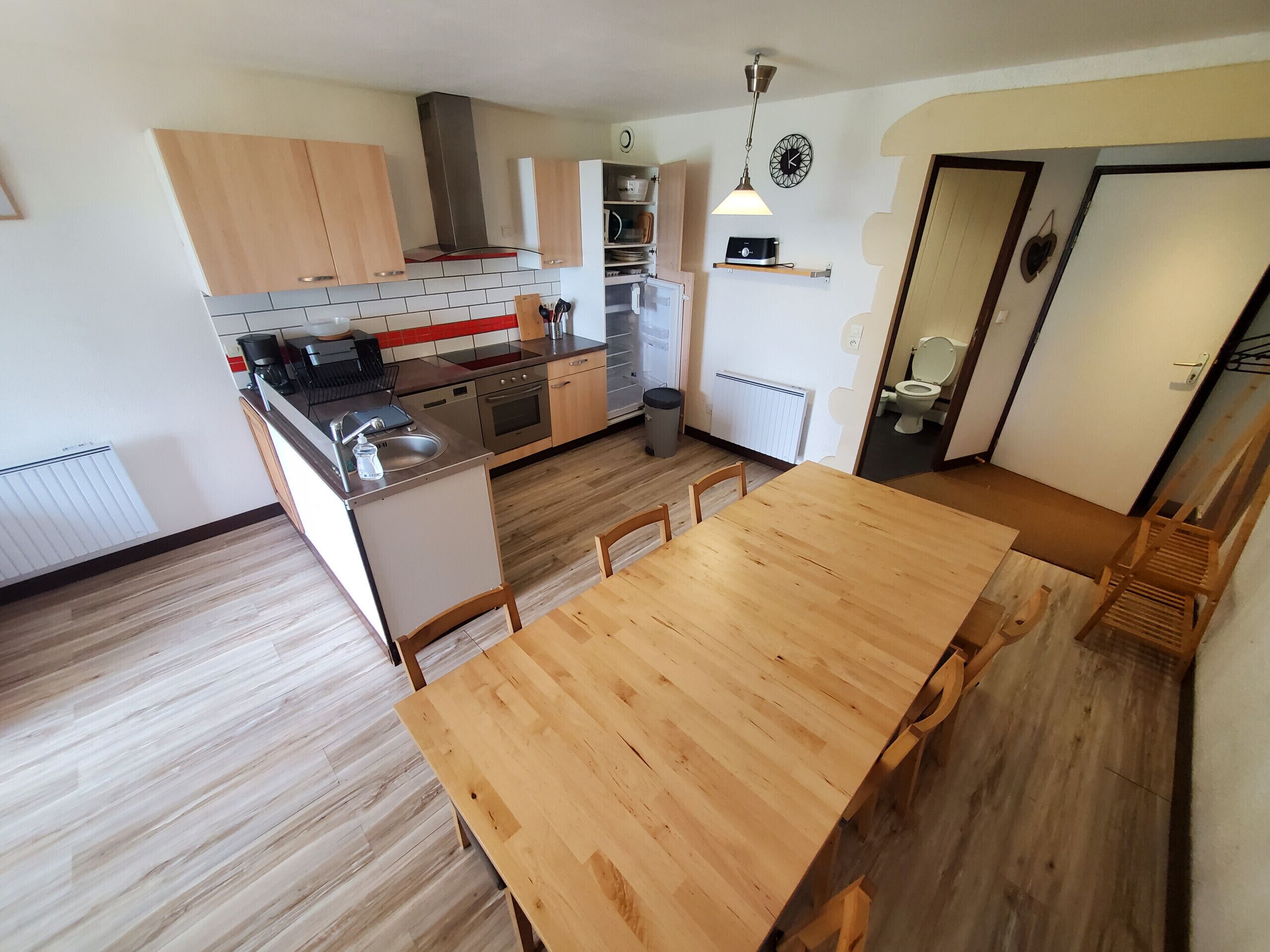 A modern kitchen with wooden cabinets, a stainless steel range, and a wooden dining table.