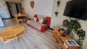 A living room with a sofa, a dining table, and a TV.