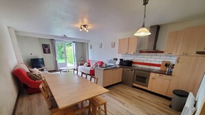 A modern kitchen with wooden cabinets, a dining table, and a red sofa.