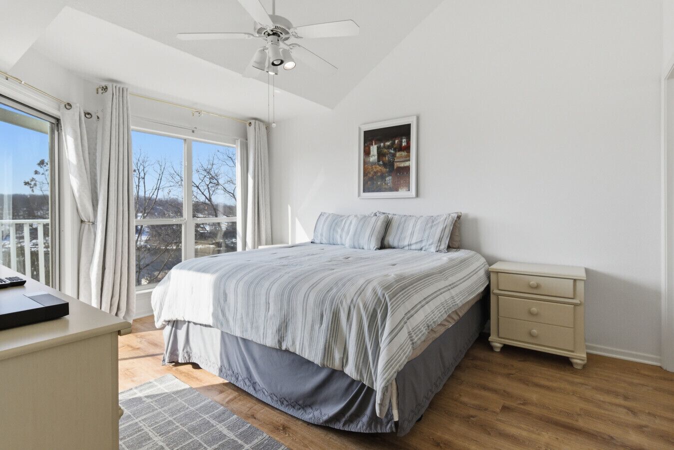 A bedroom with a bed, bedside table, and a ceiling fan.