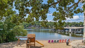 A beach area with a wooden play structure, a slide, and several colorful chairs. - Blue Oasis - Two Pools, Beach, & More! (Osage Beach)