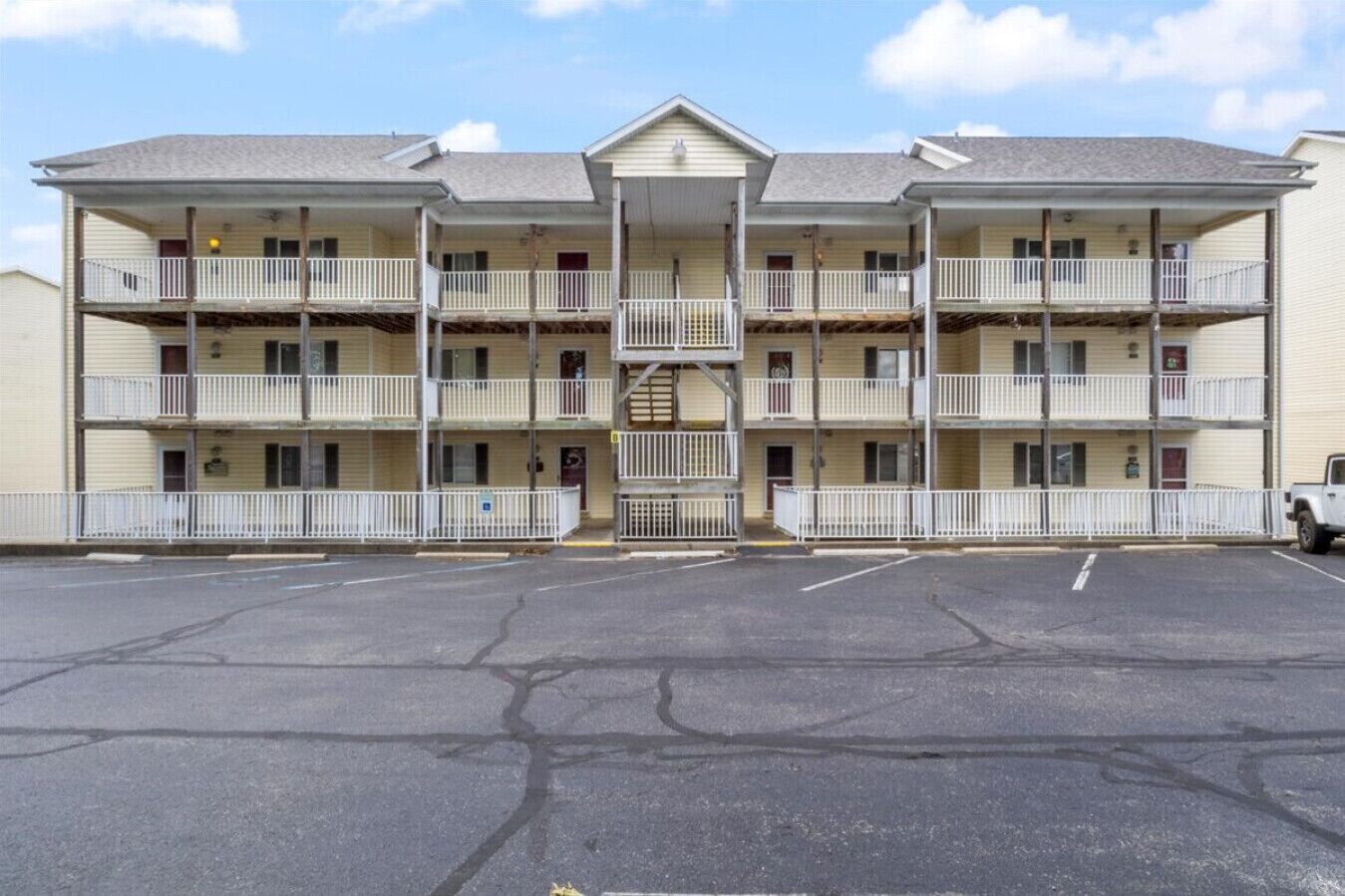 Un motel de varios pisos con entrada central, balcones y estacionamiento.