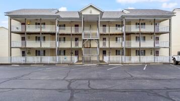 Un motel de varios pisos con entrada central, balcones y estacionamiento.
